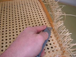 Using a sharp utility knife to cut excess rattan webbing.